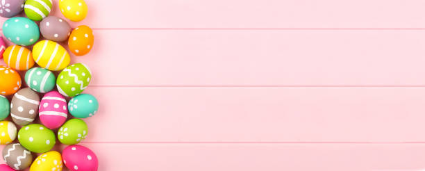 istock Colorful Easter banner with a side border of Easter Eggs over a pink wood background with copy space 1205064919