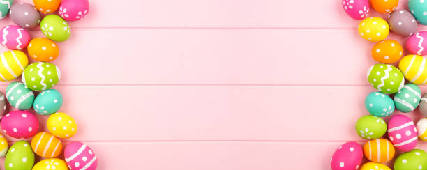istock Colorful Easter banner with a double sided border of Easter Eggs over a pink wood background with copy space 1205065268