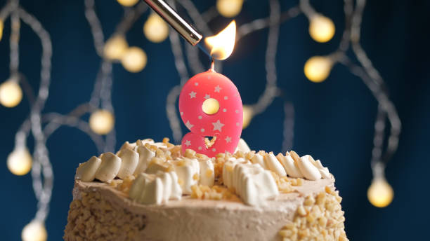 istock Birthday cake with 9 number pink candle on blue backgraund set on fire by lighter. Close-up view 1205065851