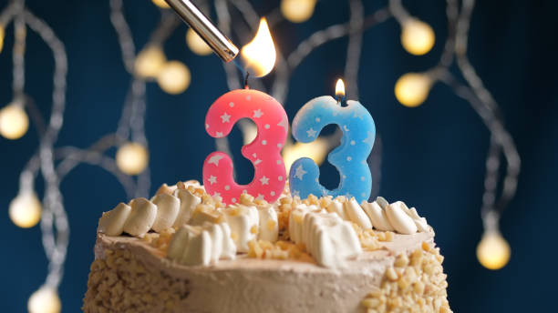 Birthday cake with 33 number pink candle on blue backgraund set on fire by lighter. Close-up view Birthday cake with 33 number candle on blue backgraund set on fire by lighter. Close-up view candles number 33 stock pictures, royalty-free photos & images