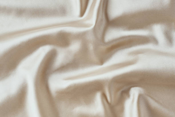 istock Golden light silk background with a folds.  Abstract texture of rippled satin surface 1205067065