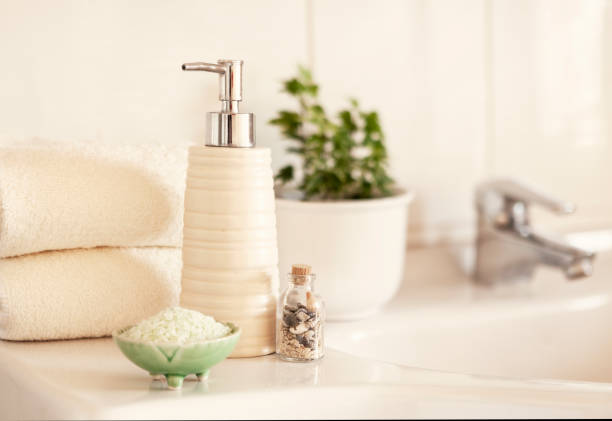 istock Ceramic soap, shampoo bottle, bowl with bath salt and white cotton towels on Blurred bathroom interior background with sink and faucet. 1205067076
