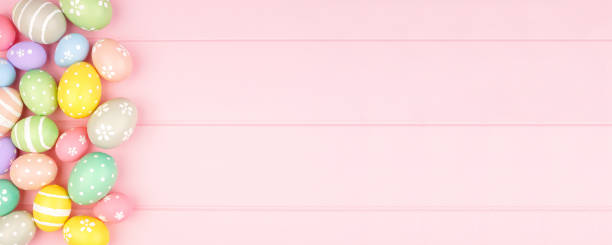 istock Easter banner with side border of pastel Easter Eggs over a pink wood background with copy space 1205067194
