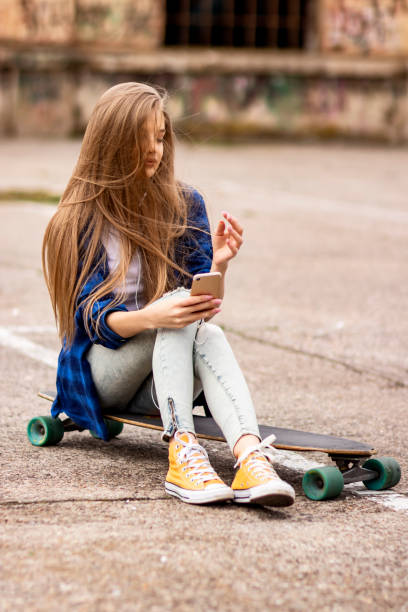 istock Female Skateboarder is Using a Mobile Phone in the Street 1205071212