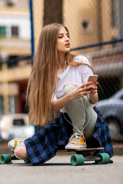 istock Having fun . Female Skateboarder is Using a Mobile Phone in the Street 1205072846
