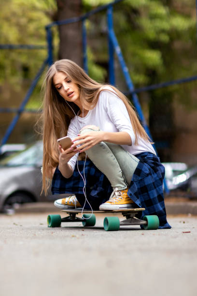 istock Having fun . Female Skateboarder is Using a Mobile Phone in the Street 1205072923