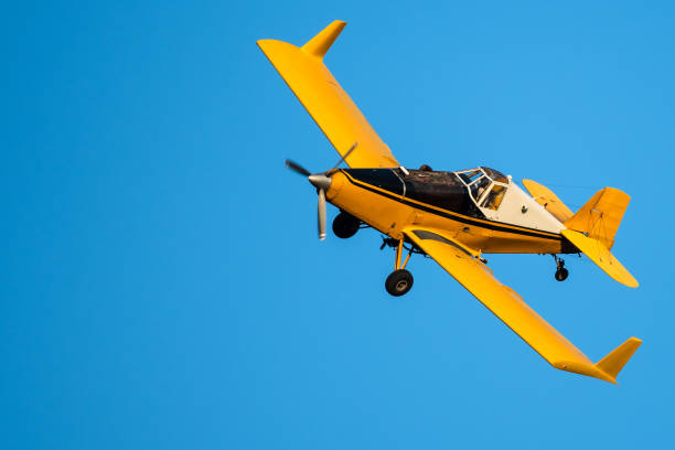 istock Yellow Crop Dusting Plane Flying in a Blue Sky 1205073096