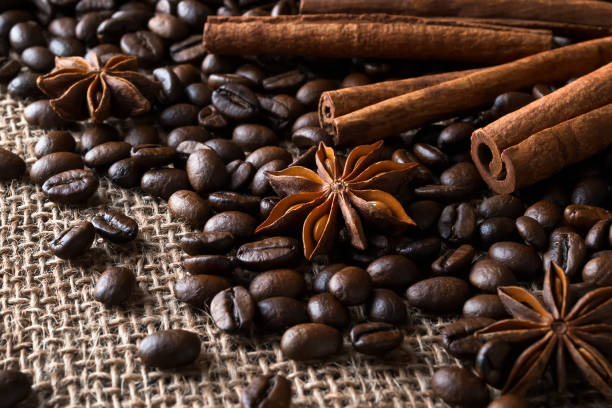 istock Cinnamon sticks and star anise on a roasted coffee beans over a sackcloth background. Low key image of coffee drink ingredients. 1205075266