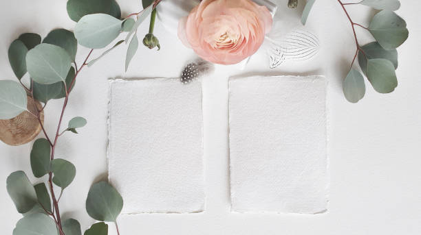 istock Blank white Wedding Greeting invitation card mockup silver eucalyptus leaves branch, blush pink buttercup ranunculus flower on textured paper table backgound. Elegant modern template Flat lay top view 1205076695