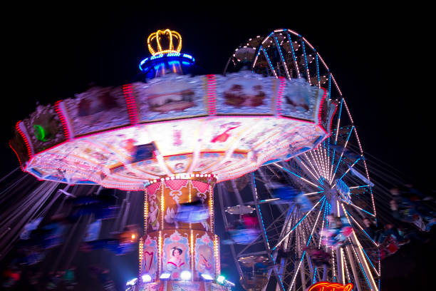 istock Motion blurred carousel by night with ferris-wheel in the background 1205077438