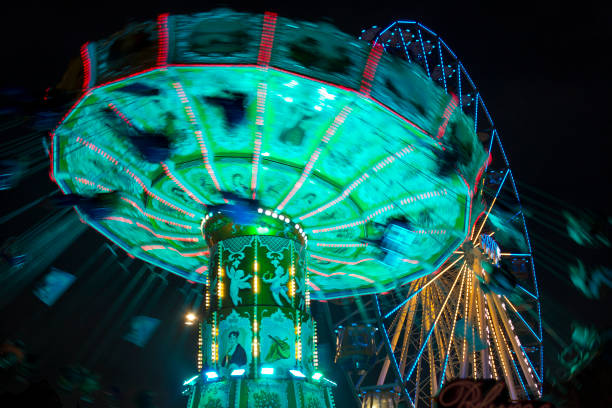 istock Motion blurred carousel by night with ferris-wheel in the background 1205077442