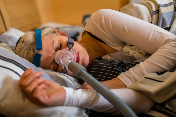 mujer que duerme con máscara cpap debido a la apnea obstructiva del sueño - apnea del sueño fotografías e imágenes de stock