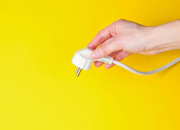 istock Female hands power plug on yellow background. Minimalism. Top view 1205080830