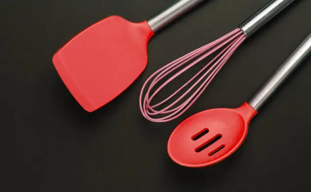 Silicone kitchen tools on a black background. Top view.