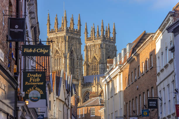 Low Petergate and York Minster. York, UK. February 6, 2020.  Low Petergate in York with its shops and the towers of York Minster in the background. york yorkshire stock pictures, royalty-free photos & images