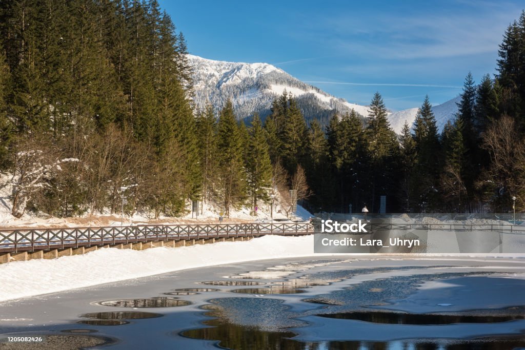 Jasna ski resort in Low Tatras, Slovakia (Slovensko). Beautiful winter landscape with artificial lake surrounded by fir tree forest Jasna ski resort in Low Tatras, Slovakia (Slovensko). Beautiful winter landscape with artificial lake surrounded by fir tree forest, mountains and blue sky Low Tatras Stock Photo