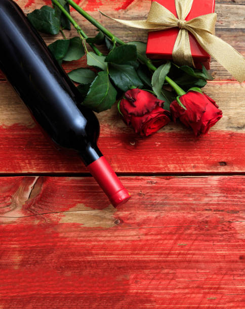istock Valentines day. Red wine bottle, roses and a gift on wood 1205082629