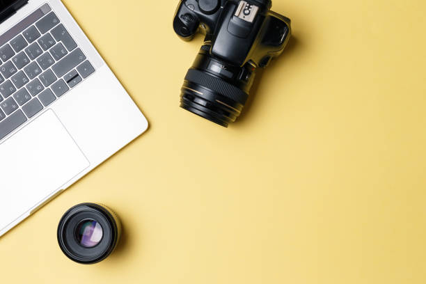 istock Photographer's workplace on a yellow background. Modern laptop, digital camera, lens, battery, smartphone. Minimalism. Top view. Copy space. Equipment for the photographer. The concept of freelancing 1205085992