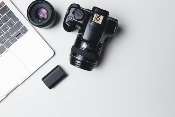 istock Photographer's workplace on a white background. Modern laptop, digital camera, lens, battery, smartphone. Minimalism. Top view. Copy space. Equipment for the photographer. The concept of freelancing 1205087143