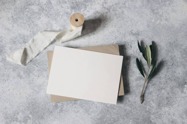 istock Feminine wedding stationery, desktop mock-up scene. Blank greeting card, craft envelope with olive branch and silk ribbon.Grunge table background. Flat lay, top view. Mediterranean summer design. 1205087643