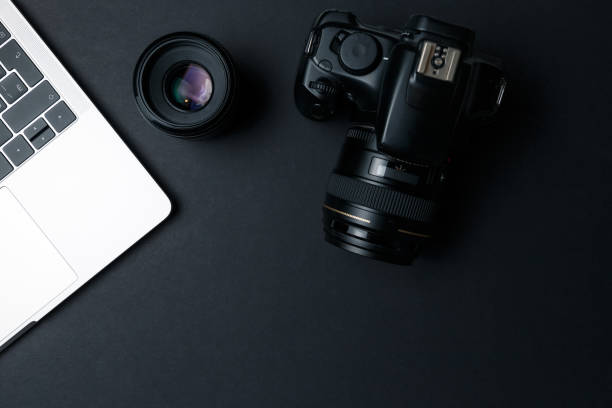 istock Photographer's workplace on a dark background. Modern laptop, digital camera, lens, battery, smartphone. Minimalism. Top view. Copy space. Equipment for the photographer. The concept of freelancing 1205087804