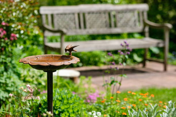 istock Idyllic green springtime garden with bench and bird bath 1205088417