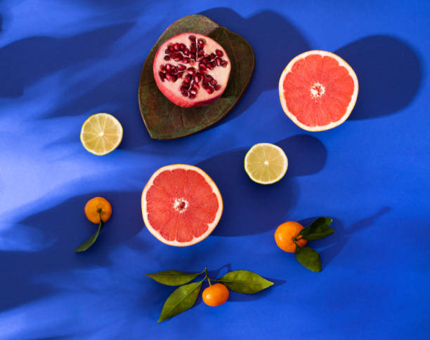 Composition with citrus fruits on a bright blue background. Bright light, contrasting shadows.