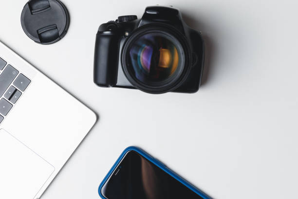 istock Photographer's workplace on a white background. Modern laptop, digital camera, lens, battery, smartphone. Minimalism. Top view. Copy space. Equipment for the photographer. The concept of freelancing 1205090446