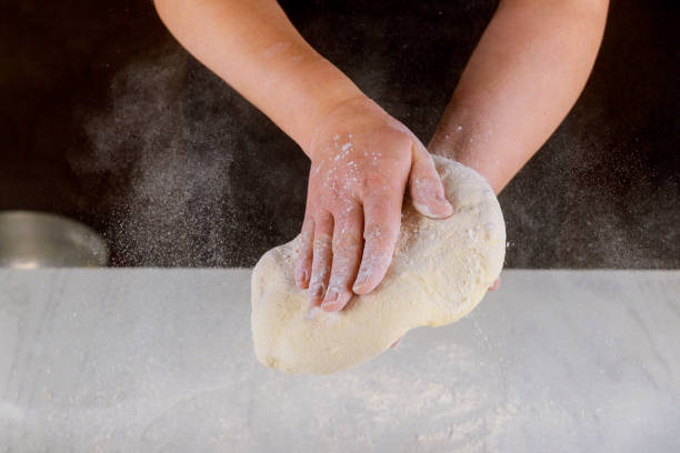 istock Person kneading pizza dough in hands for making pizza. 1205097673