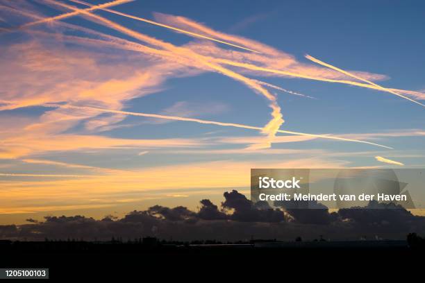 Contrails High Up In The Sky Are Colorful Illuminated By The Light Of The Setting Sun Stock Photo - Download Image Now
