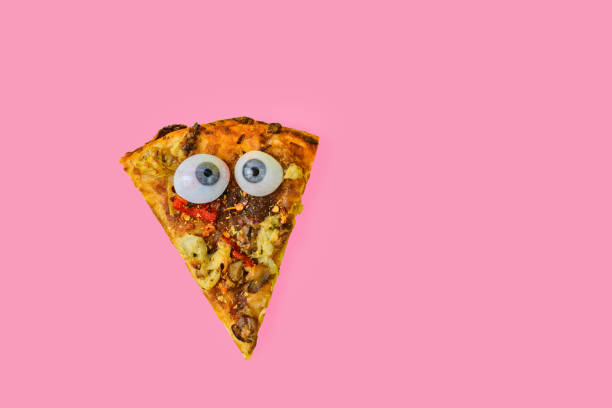 This is a color photograph of a slice of no cheese vegan pizza with googly eyes on a bright colored background.