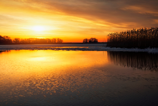 Natural lake completely frozen in the black forest with a prominent rock in the foreground.