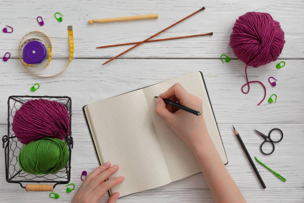 istock Background with knitting and crocheting tools and accessories for starting a project, woman hands writing 1205112238