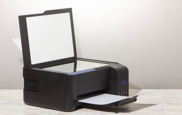 Black copier on white wooden table, closeup.