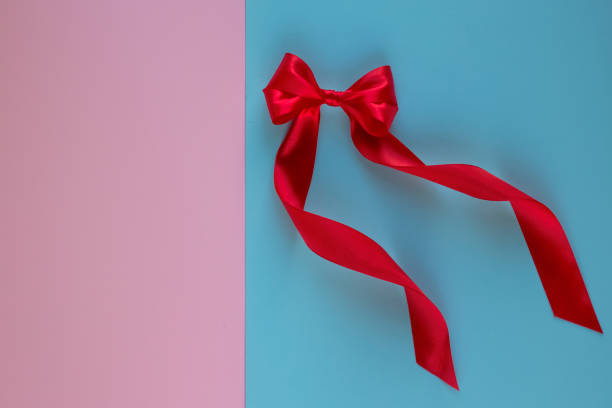 istock Bright red bow made from silk ribbon on blue background with copy space on pink background. Festive concept. Birthday greetings concept. Close up 1205116051