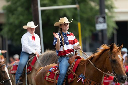 Arlington, Texas, USA - July 4, 2019: Arlington 4th of July Parade, Young woman riding a horse down route at the parade