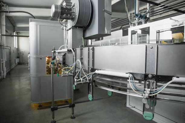 istock Machine for blowing plastic bottles from PET preforms, industrial conveyor belt in factory interior 1205122797