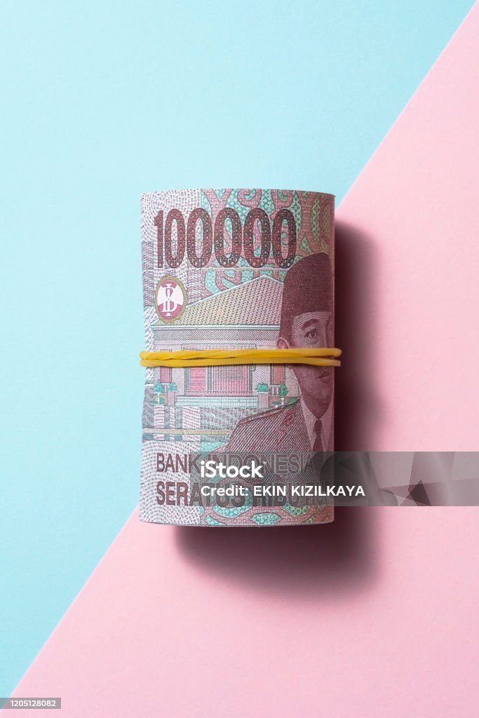 Indonesian rupiah roll on two tone color background Indonesian rupiah roll on blue and yellow two tone color background Indonesian Currency Stock Photo