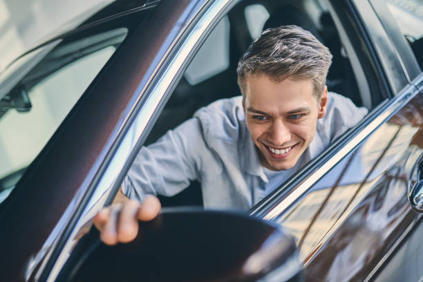 istock Happy buyer adjusting rear view mirrors in new car. 1205128128