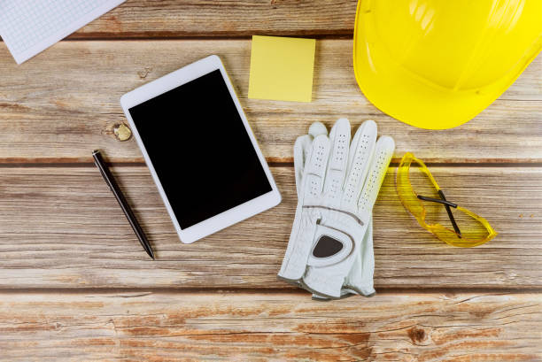 istock Architect engineer workplace standard construction safety equipment on gloves yellow helmet and tablet pc 1205128587