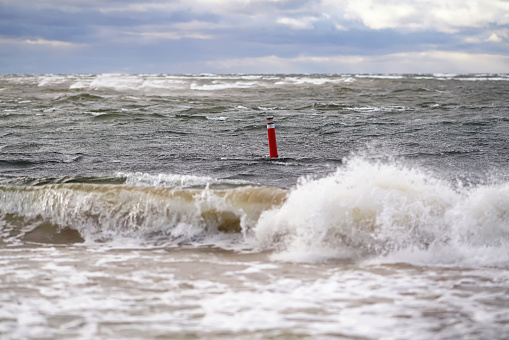 The Baltic sea during the storm in Riga, Latvia. The focus is on a red floating navigational buoy