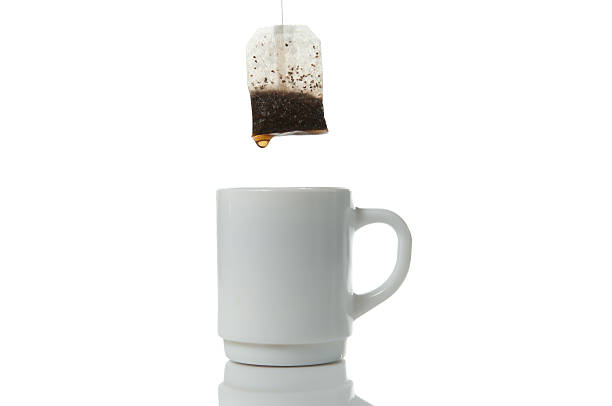 Tea bag over mug on a white background stock photo