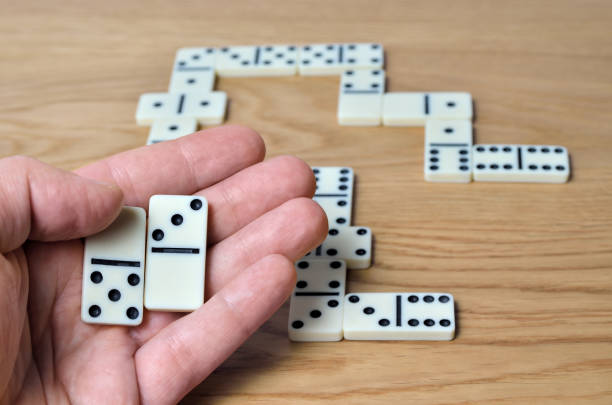 istock Playing dominoes on a wooden table. Dominoes game concept 1205130444