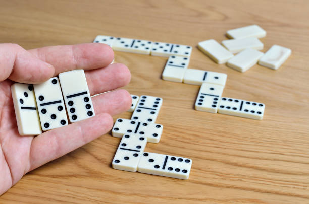 istock Playing dominoes on a wooden table. Dominoes game concept 1205130514