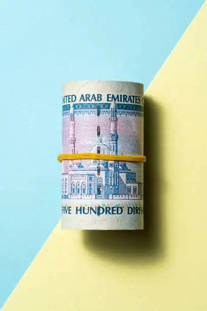United Arab Emirates dirham roll on blue and yellow two tone color background