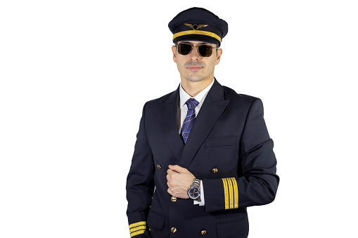 Male pilot with uniform + jacket, wearing pilot glasses and pilot hat, posing with confidence, holding his jacket with hand