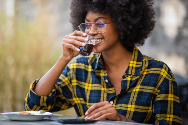 istock young afro american woman smiling and drinking coffee 1205138388