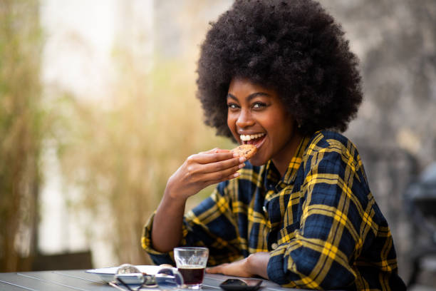 istock Close up happy young black woman eating cookie 1205138401