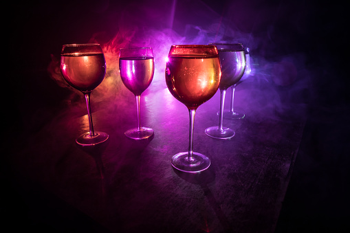 Goblet of wine on wooden table with beautiful toned lights on background. Glasses of wine on dark background. Selective focus. Club drink concept