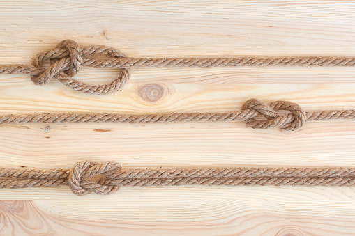 Marine knots used in yachting: figure eight knot, square knot, bowline knot. Nautical knots on wooden background.